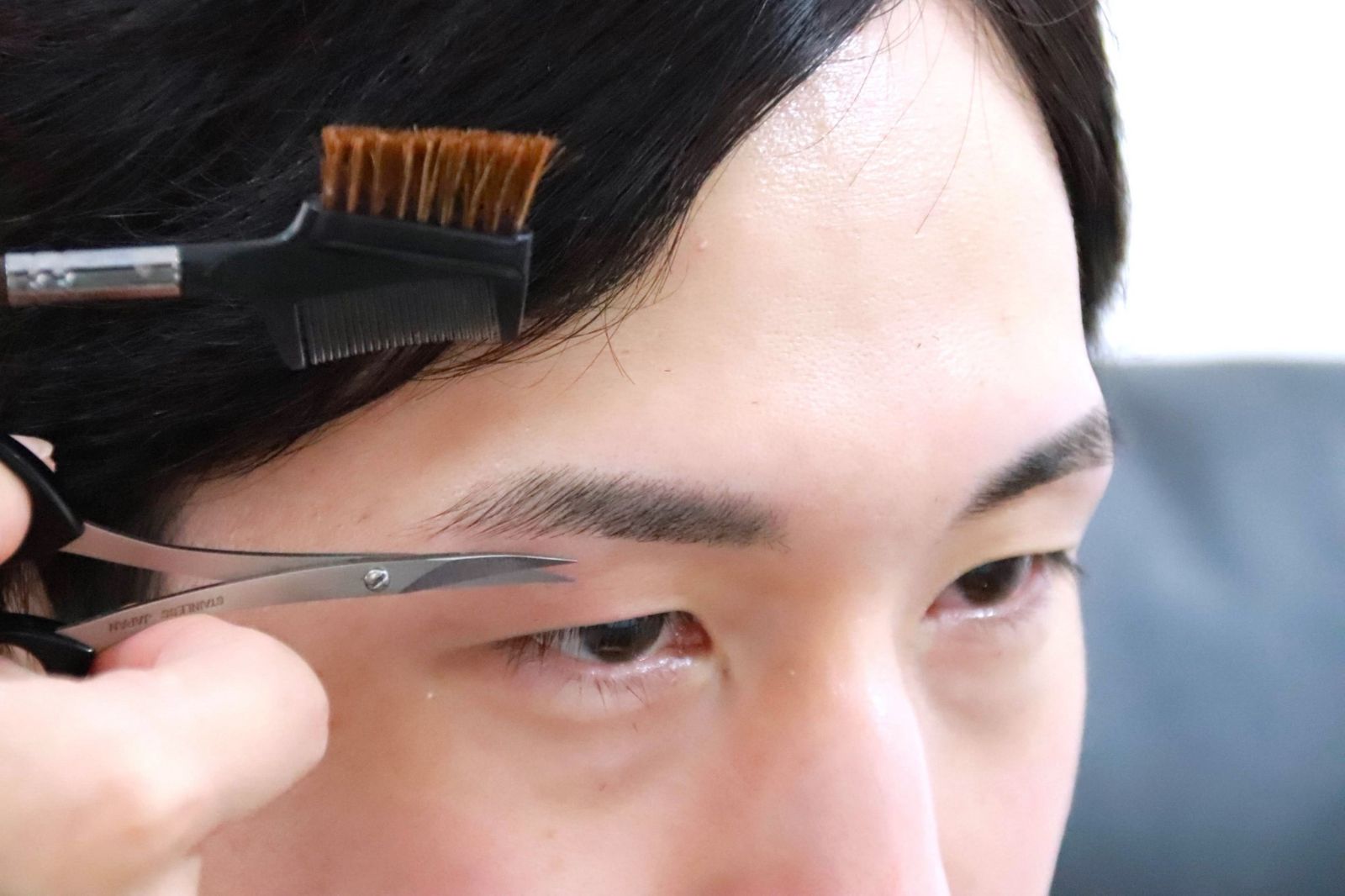 ハサミで眉毛の長さを整える施術